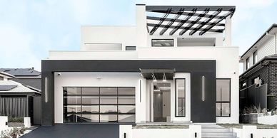 Modern white and black two-story house with large garage doors.