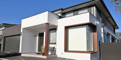 Modern two-story house with a clean white exterior and large windows.