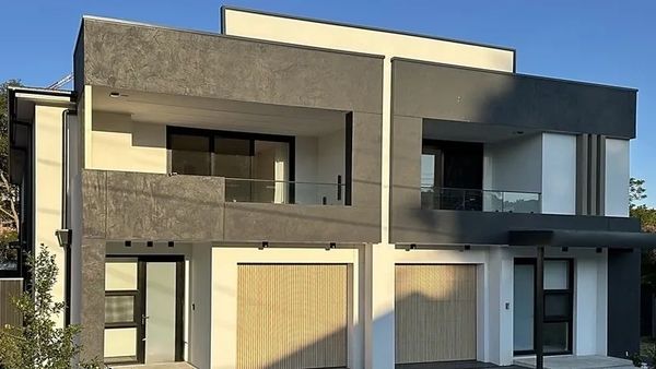 Modern two-story house with a minimalist design and large windows.