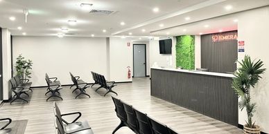 Modern, clean medical waiting room with rows of black chairs and a reception desk.