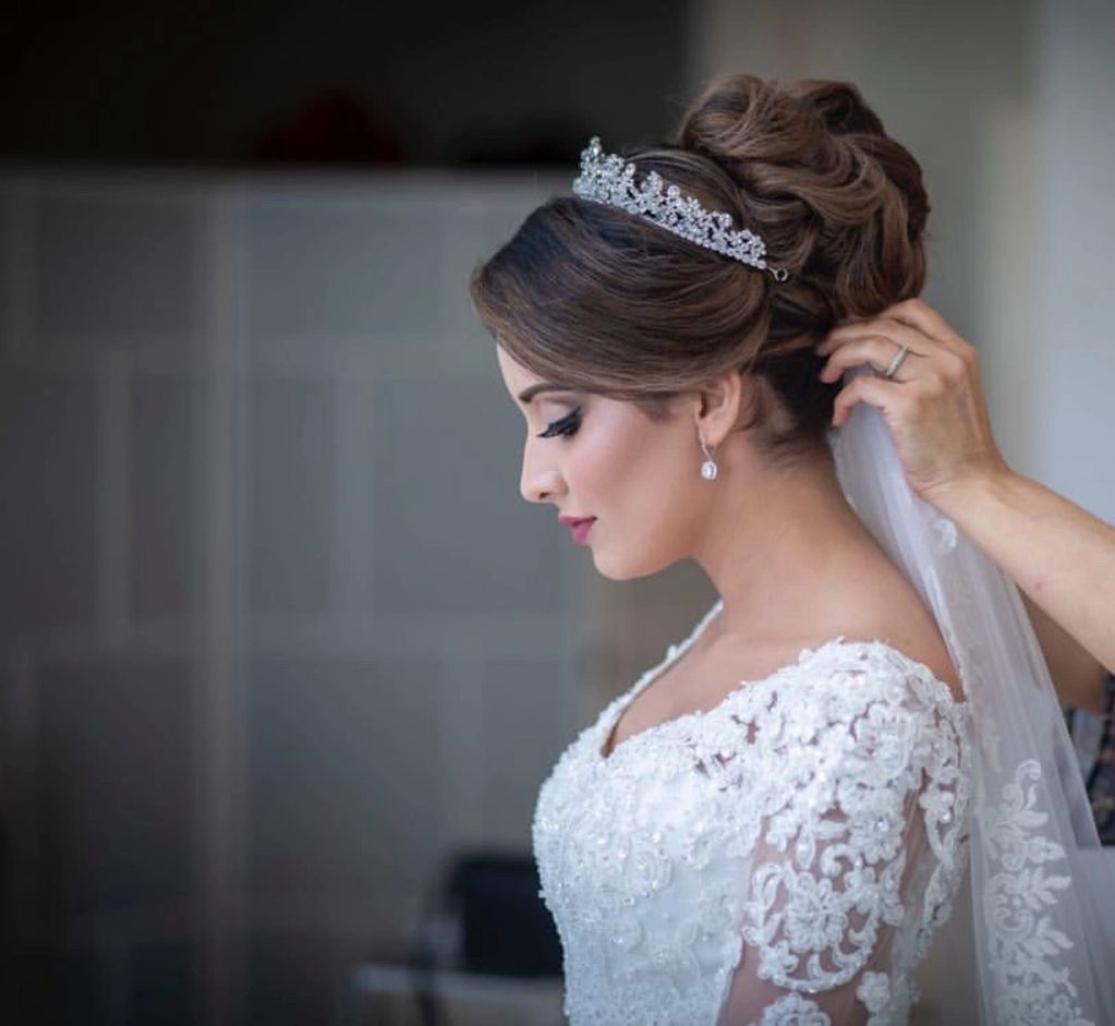 Classic and elegant bridal hairstyle and makeup by Zina Edda. Final touches on her veil. 