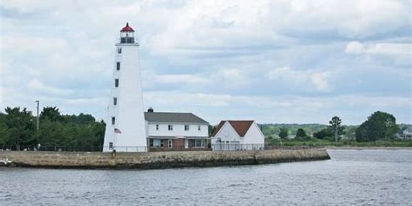 A tall white lighthouse on a small peninsula by the water.