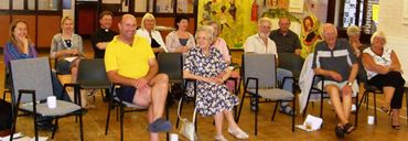 a group of people of different ages sit in chairs smiling at the camera