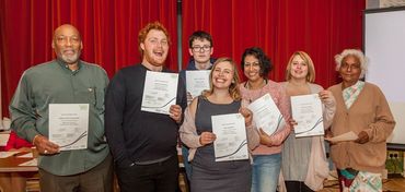 a group of people of a range of ages, genders and ethnicities hold certificates. they are smiling