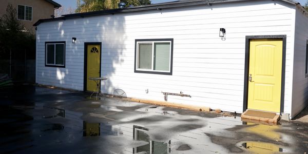 White building with two yellow doors reflected in wet ground.