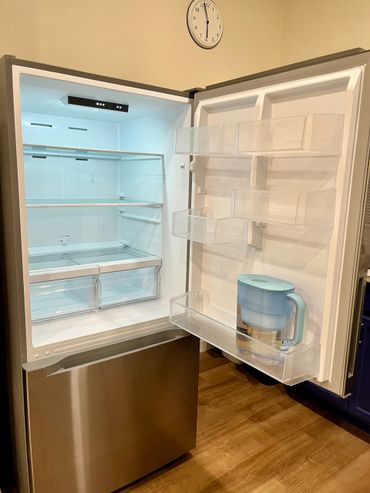 Open empty refrigerator with a water filter pitcher inside the door.