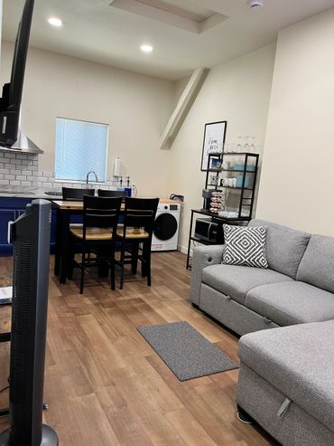 Cozy modern living space with gray sofa, dining table, and kitchen amenities.