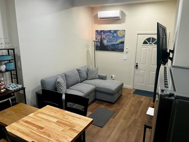 Cozy living room with gray sectional, dining area, and Starry Night painting on wall.