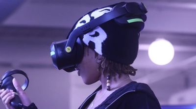 Person wearing a VR headset and holding a controller in a dimly lit space.