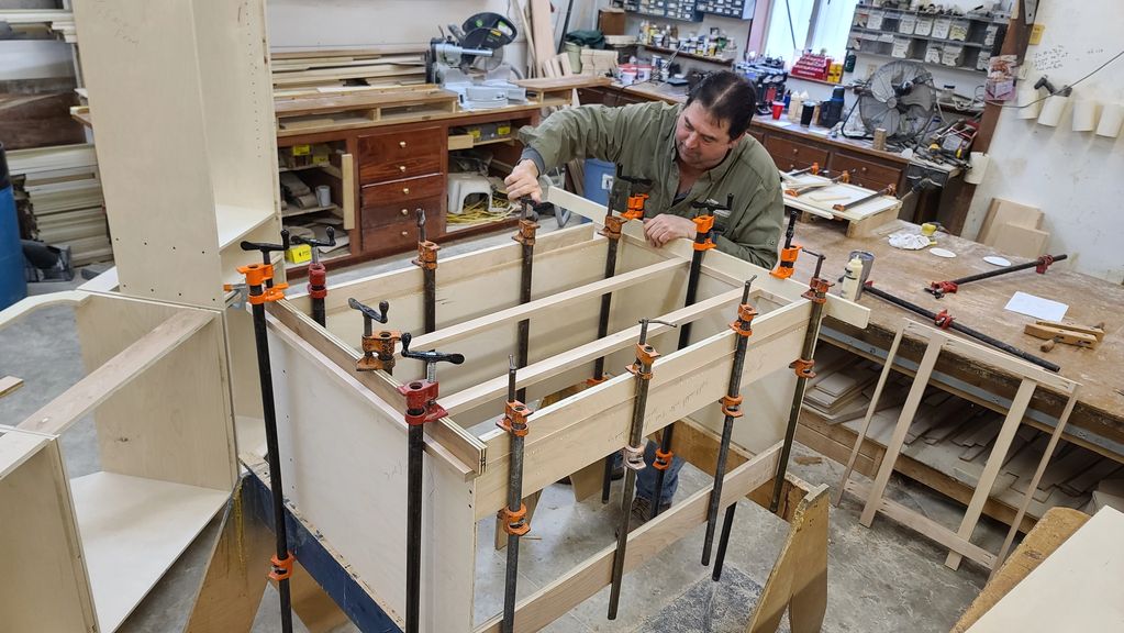 Man working on a woodworking project with clamps in a workshop.