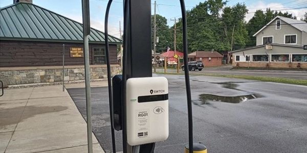 Lite-On brand level 2 chargers mounted on a post in a retail parking lot.