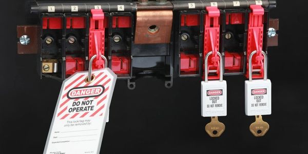 Electrical panel switches locked with danger tags and padlocks for safety.