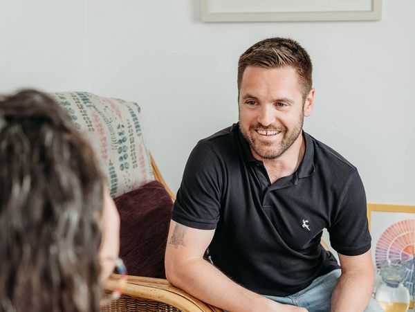 Smiling man engaged in a friendly conversation indoors.