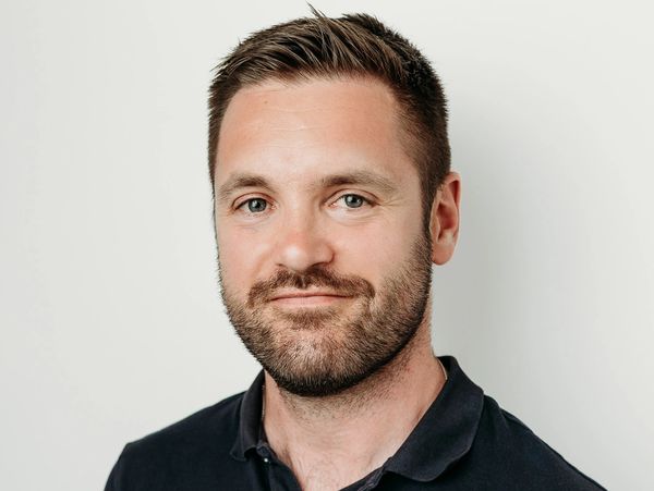 Man with short hair and beard wearing a dark polo shirt.