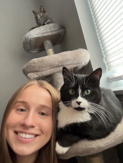 Smiling girl with two cats on a cat tree.