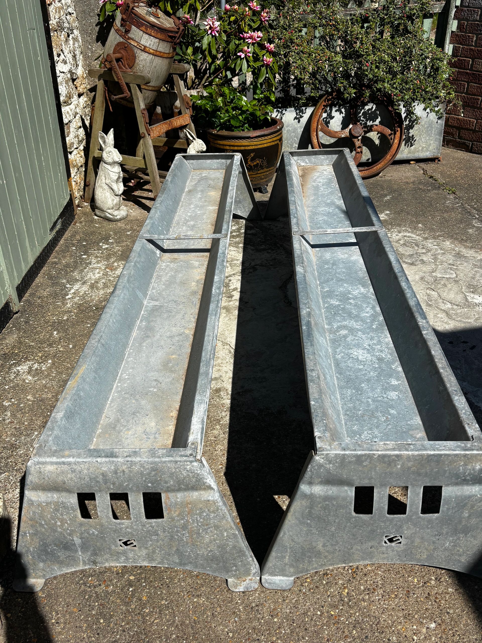 Two long galvanized metal troughs on the ground.