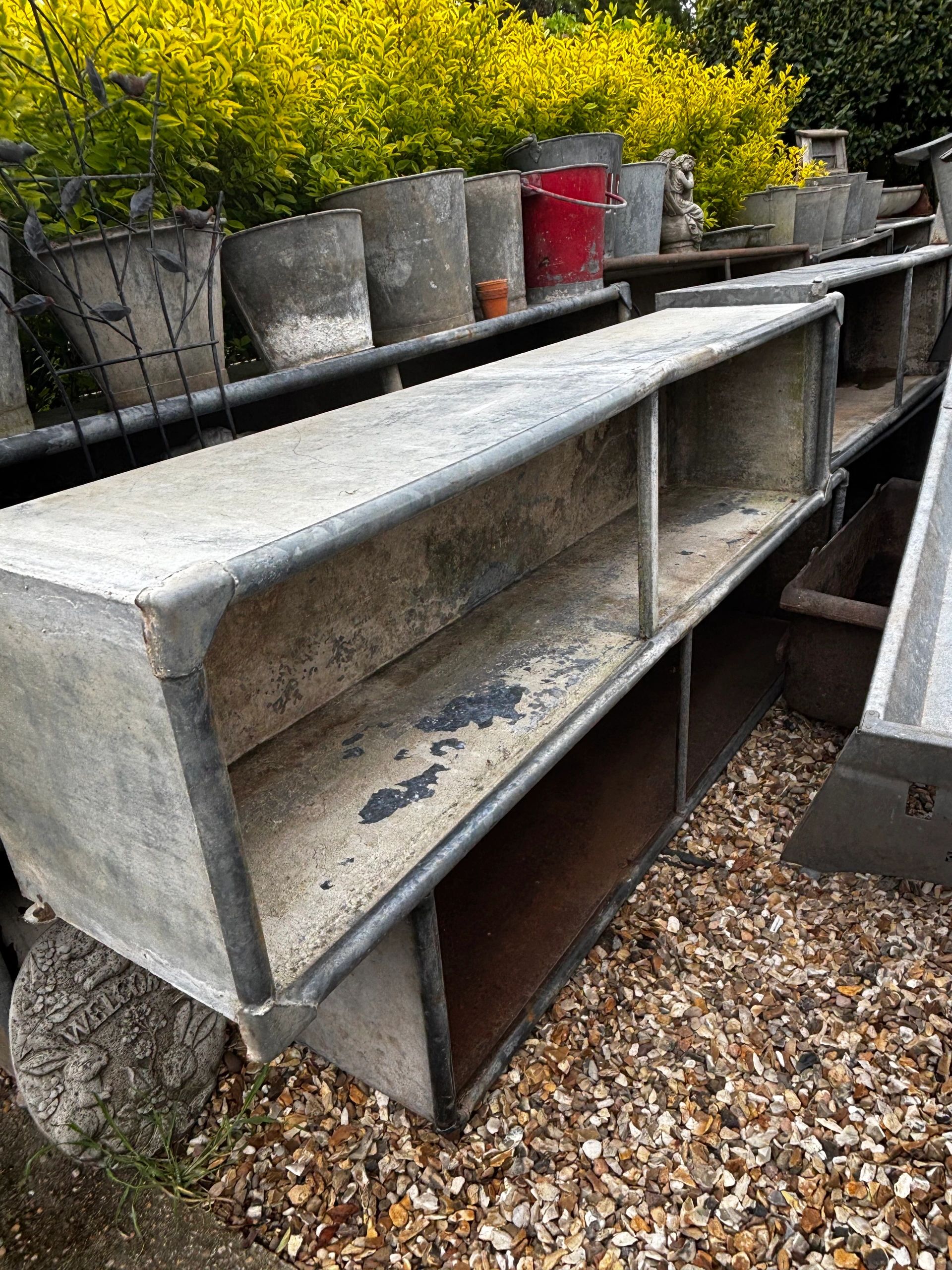 Stacked metal troughs with a stone marker nearby.