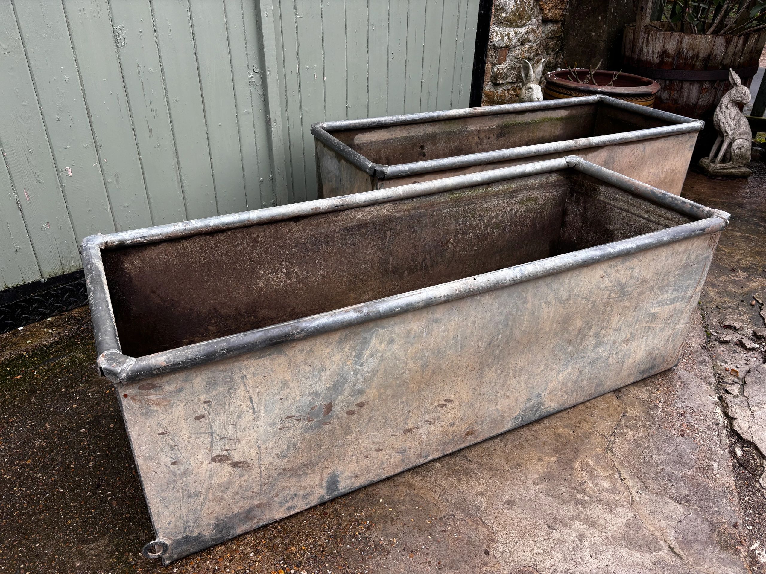 Two empty rectangular metal containers on a concrete floor.