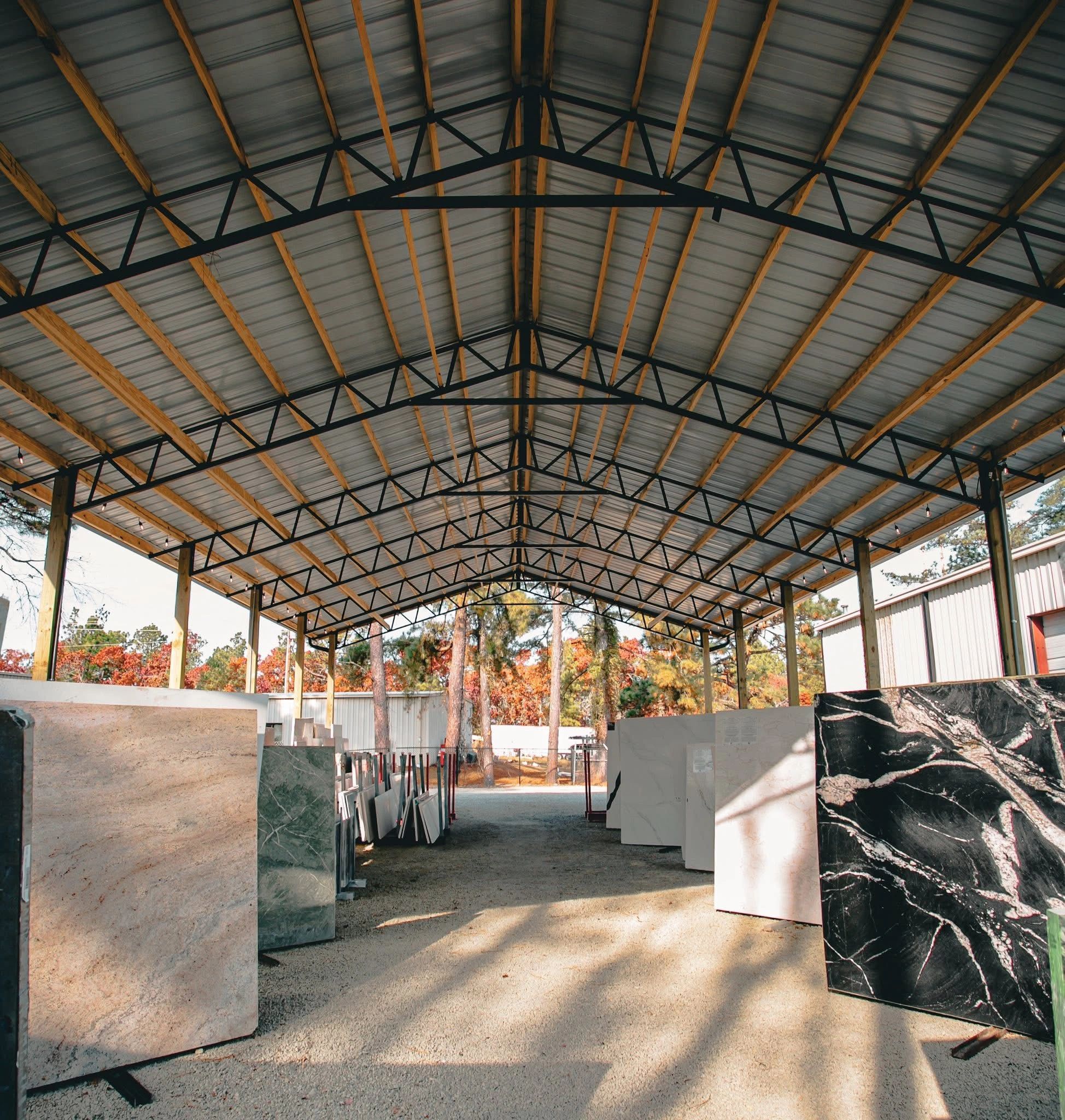 Outdoor covered area displaying large stone slabs for construction or design.