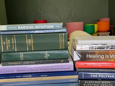 Stack of books on alternative healing and chiropractic methods.