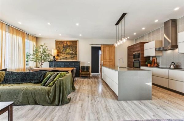 Modern open-plan kitchen and living room with wooden flooring and natural light.
