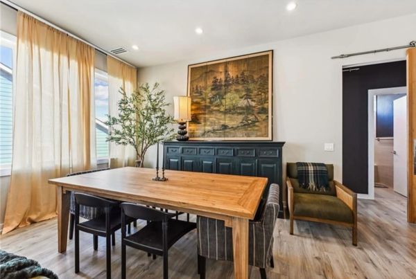 Modern dining room with wooden table, black chairs, and large wall art.