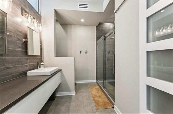 Modern bathroom with sleek sink, glass shower, and neutral tones.