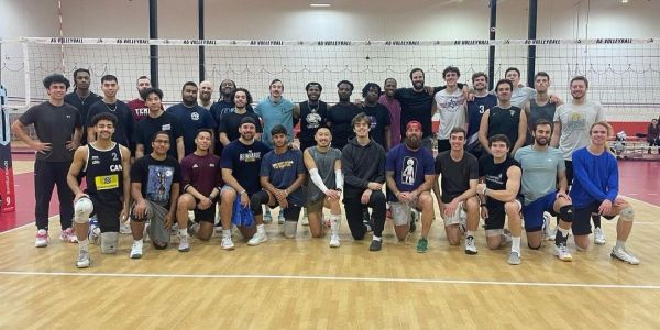 A large group of volleyball players posing on an indoor court.