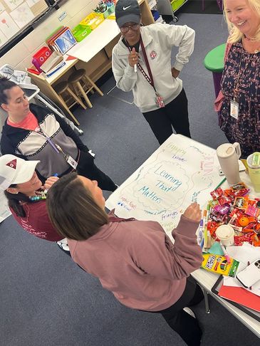A group of educators collaborating around a table with colorful notes and snacks.