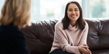 Young adult seated, smiling, while seeing a psychologist