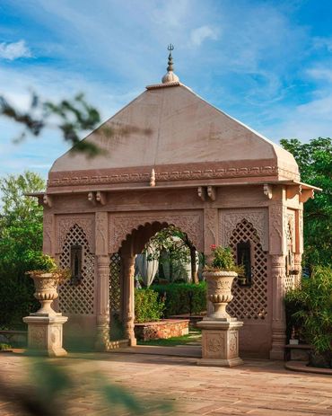 Ornate stone pavilion with plants around.