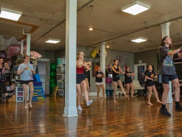Group of people dancing in a studio with wooden floors.
