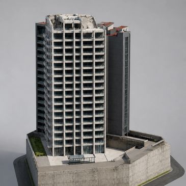 A tall, damaged concrete building with many windows and a flat roof.