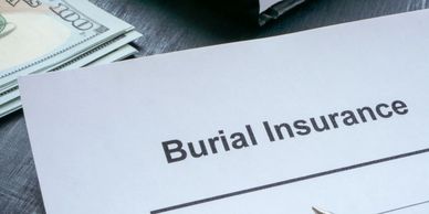 Burial insurance form with pen and cash on desk, representing final expense coverage.