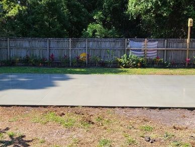 A professionally finished concrete slab installed in a landscaped backyard.