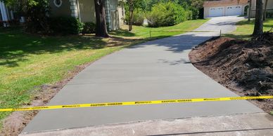 Freshly poured concrete driveway with caution tape on a sunny day.