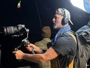 Man operating a camera at night with headphones.