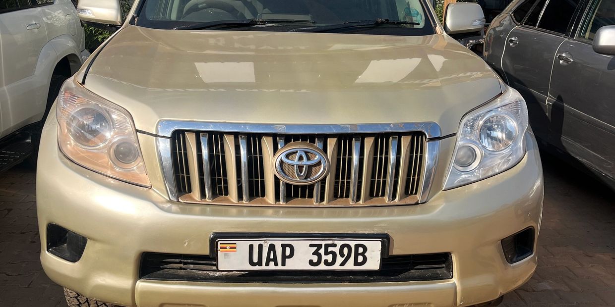 Front view of a gold Toyota SUV with Ugandan license plate.