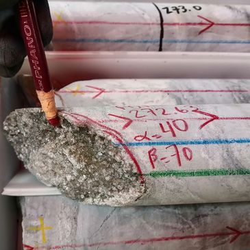 Muestra de núcleo de roca con anotaciones y una herramienta marcadora.