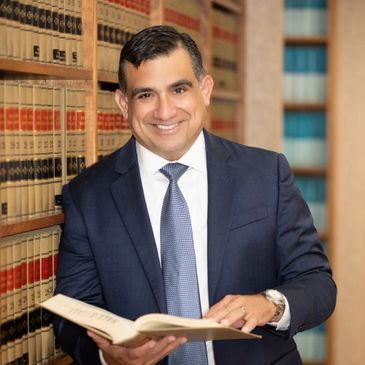 Professional man in suit holding a book in a law library.