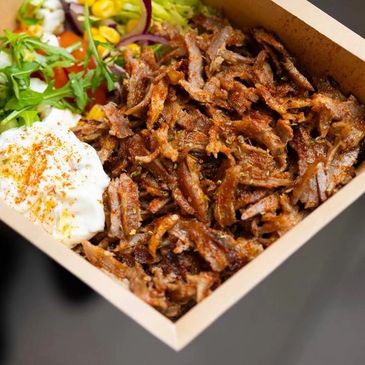 A box of crispy shredded meat with salad and creamy sauce.