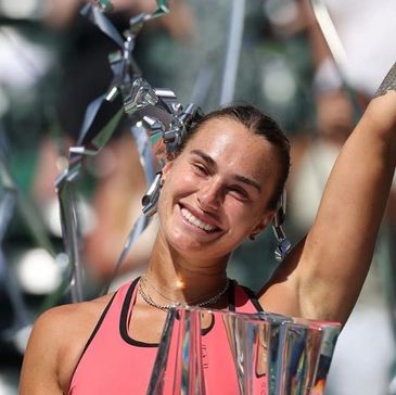 Smiling female athlete celebrating victory with trophies.