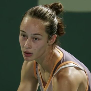 A focused female athlete with a top knot hairstyle during a sports event.