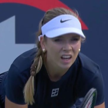 Female tennis player focused during a match, wearing a white Nike visor.
