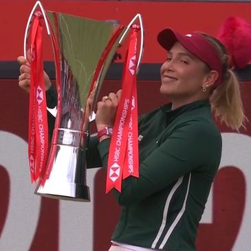 Golfer holding HSBC Champions trophy with a smile.