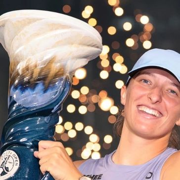 Woman smiling and holding a large trophy.