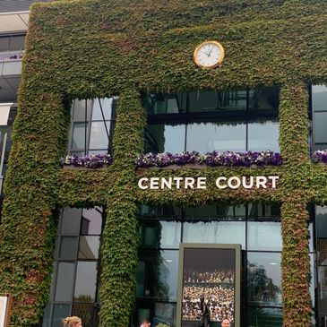 Entrance of Centre Court covered with green ivy and a clock above.