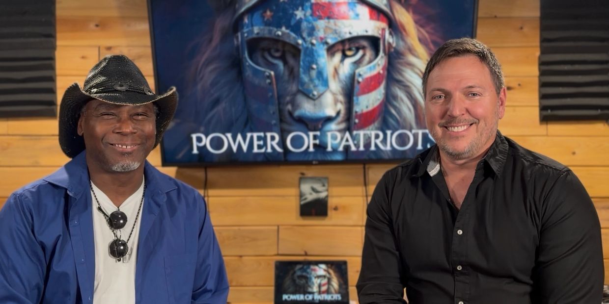 Two men smiling in front of a 'Power of Patriots' banner with a lion wearing a patriotic helmet.