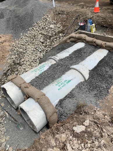Two concrete pipes laid on gravel with straps.