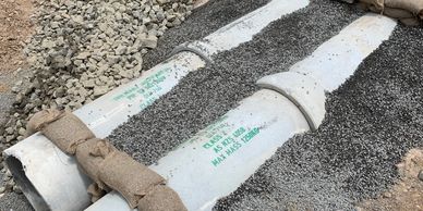 Two concrete pipes laid on gravel with straps.